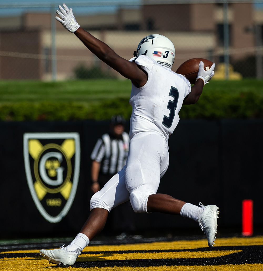 Levy Hamer celebrates in the Gustavus Adolphus end zone with his arms extended. (Photo by Tim Kruse for UW-Stout athletics)